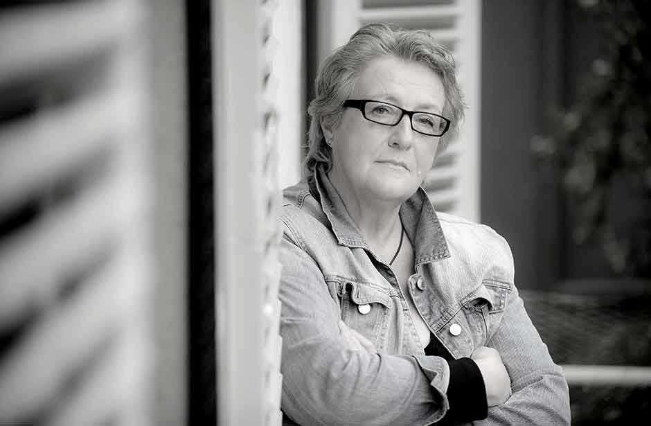 Frau lehnt sich gelassen an einer Wand.